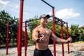 Fitness man training chest with resistance bands at street gym yard. Outdoor workout. Body workout with equipment