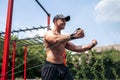 Fitness man training chest with resistance bands at street gym yard. Outdoor workout. Body workout with equipment