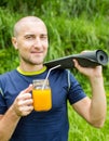Fitness man with yoga mat holding a glass of orange juice Royalty Free Stock Photo