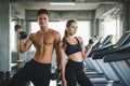 Fitness man and woman holding dumbbell standing posing near treadmill. Muscular couple training at the gym Royalty Free Stock Photo