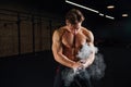 Fitness model trainer rubs his hands with chalk and talc so that fingers do not slip or slide.