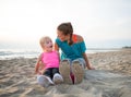 Fitness mother and surprised baby girl on beach Royalty Free Stock Photo