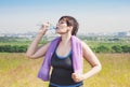 Fitness plus size woman with towel drinking water Royalty Free Stock Photo