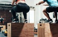 When fitness says jump, do. two unrecognizable sportspeople box jumping while working out in a gym.