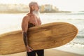 Fitness senior having fun surfing at sunset time - Sporty bearded man training with surfboard on the beach Royalty Free Stock Photo