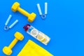 Fitness set with bars, towel, bottle of water and wrist builder on blue background top view mock up