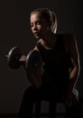 Fitness sexy girl with dumbbells on a dark background. Athlete doing exercises in the gym Royalty Free Stock Photo