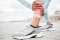 Fitness, shoes and injury with a sports woman holding her leg in pain during exercise or a workout outdoor in the city