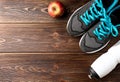 Fitness sneakers, bottle of water and red apple on wooden. Royalty Free Stock Photo