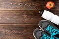 Fitness sneakers, bottle of water and red apple on wooden. Royalty Free Stock Photo