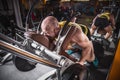 Fitness and Sport. Athletic man doing exercises on legs in gym among other people. Royalty Free Stock Photo