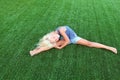 Fitness, sport, exercising, stretching and people concept - smiling blond girl doing splits on the grass Royalty Free Stock Photo