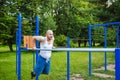 Fitness, sport, exercising, training and lifestyle concept. Young man doing triceps dip on parallel bars, outdoors. Royalty Free Stock Photo