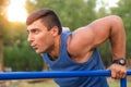 Fitness, sport, exercising, training and lifestyle concept - young man doing triceps dip on parallel bars outdoors Royalty Free Stock Photo