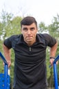 Fitness, sport, exercising, training and lifestyle concept - young man doing triceps dip on parallel bars outdoors. Royalty Free Stock Photo