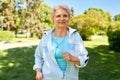 Senior woman with earphones running at summer park Royalty Free Stock Photo