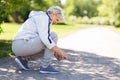 Senior woman tying sport shoe laces at summer park