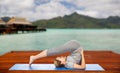 Woman making yoga in plow pose on mat outdoors