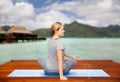 Woman making yoga in twist pose on mat outdoors