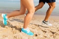 Legs of sportsmen in sneakers running along beach Royalty Free Stock Photo