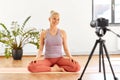 Woman with camera streaming for yoga blog at home Royalty Free Stock Photo