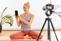 Woman with phone streaming for yoga blog at home Royalty Free Stock Photo