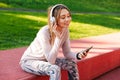 Fitness sports woman posing outdoors in park listening music with earphones using mobile phone Royalty Free Stock Photo