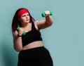 Fitness spring diet weight loss concept. Concentrating plus-size overweight woman does punches with weights dumbbells