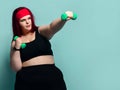Fitness spring diet weight loss concept. Plus-size overweight woman does punches with dumbbells holding arm outstretched