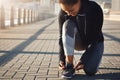 Fitness starts with that first step. a fit young woman tying her shoelaces before going for a run on the promenade.