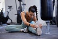 Fitness, stretching and legs of woman in gym with water bottle and audio for muscle training, energy and workout