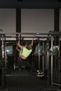 Fitness trainer pumps abs on horizontal bar in gym. Young woman with sports figure does full-body workout Royalty Free Stock Photo