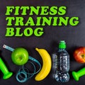 Fitness training blog concept. Dumbbell, massage ball, apples, banana, water bottle and measuring tape on black background