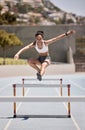 Fitness, training and woman jumping hurdles for sports, exercise and intense cardio on a running track. Black woman