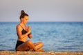 Fitness woman breathing and meditating near the sea at sunset Royalty Free Stock Photo