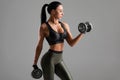 Fitness woman doing exercise for biceps on gray background. Muscular woman workout with dumbbells Royalty Free Stock Photo