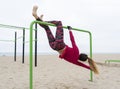 Fitness woman doing hand stand exercises performing gymnastics on calisthenics outdoor gym bars.Beach workout,street sports Royalty Free Stock Photo
