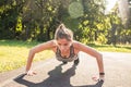 Fitness woman doing push-ups during outdoor cross training workout. Beautiful young and fit fitness sport model training