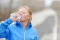 Fitness woman drinking water after beach running.