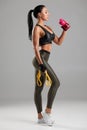 Fitness woman drinking water from a bottle, isolated on gray background. Active girl quenches thirst