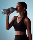 Fitness woman drinking water bottle in studio, training and workout, exercise or sports challenge on blue background Royalty Free Stock Photo