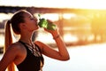 Fitness woman drinking of water after running training on morning urban city background