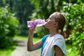 Fitness woman drinking water after running training in summer park