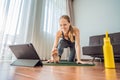 Fitness woman exercising on the floor at home and watching fitness videos in a tablet. People do sports online because Royalty Free Stock Photo