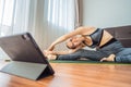 Fitness woman exercising on the floor at home and watching fitness videos in a tablet. People do sports online because Royalty Free Stock Photo