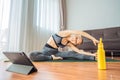 Fitness woman exercising on the floor at home and watching fitness videos in a tablet. People do sports online because Royalty Free Stock Photo