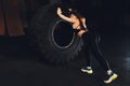 Fitness woman flipping wheel tire in gym. Fit female athlete working out with a huge tire. Back view. Sportswoman doing Royalty Free Stock Photo