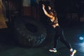 Fitness woman flipping wheel tire in gym. Fit female athlete working out with a huge tire. Back view. Sportswoman doing Royalty Free Stock Photo