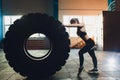 Fitness woman flipping wheel tire in gym. Fit female athlete working out with a huge tire. Back view. Sportswoman doing Royalty Free Stock Photo