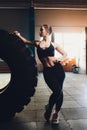 Fitness woman flipping wheel tire in gym. Fit female athlete working out with a huge tire. Back view. Sportswoman doing Royalty Free Stock Photo
